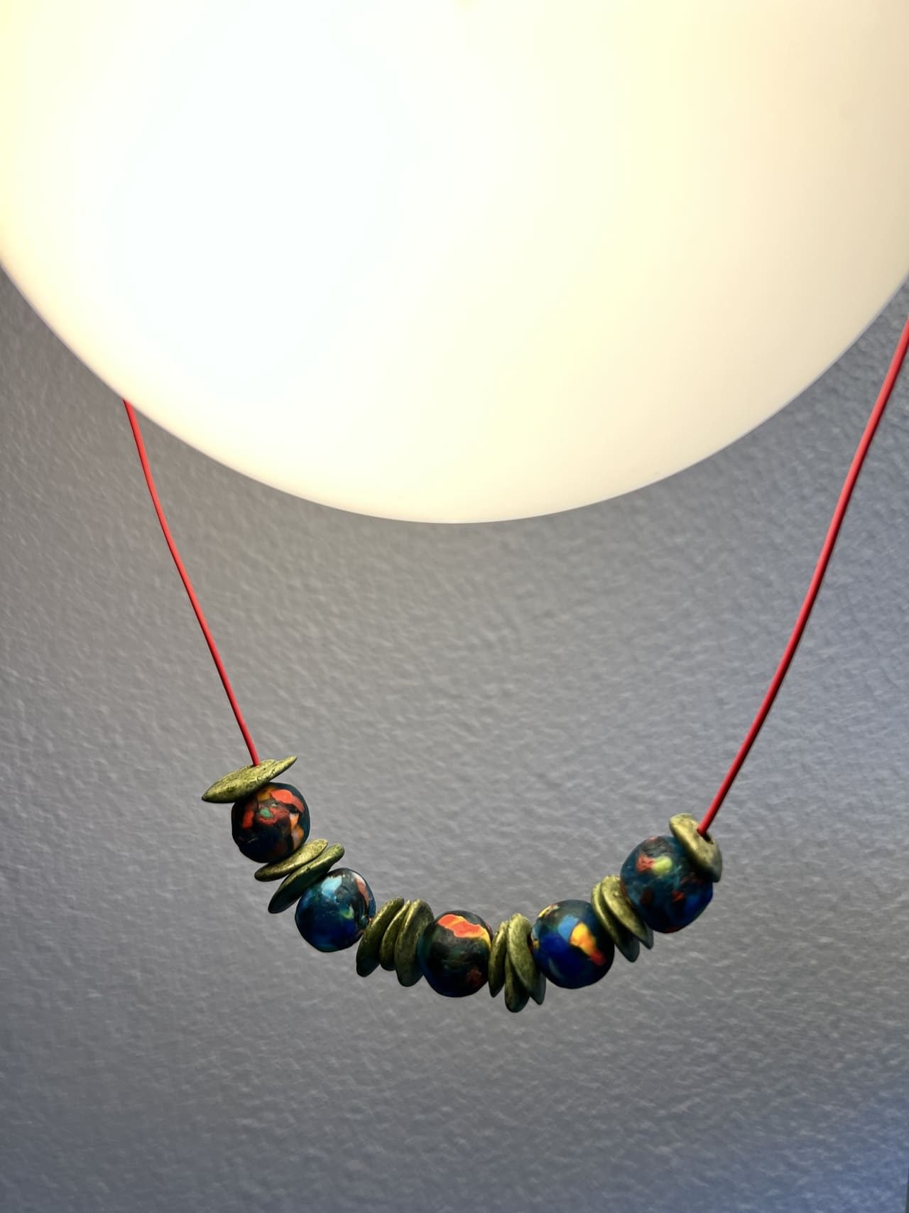 Collier fil rouge perles vertes et multicolores